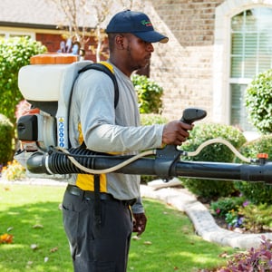 Emerald Lawns technician using a fogger for mosquito and pest control in Fort Worth, TX
