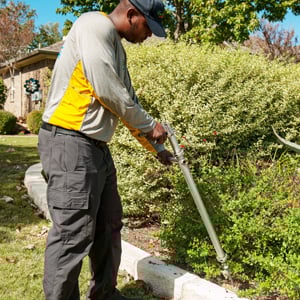 Lawn care specialist applying shrub treatment at a home in Katy, Texas
