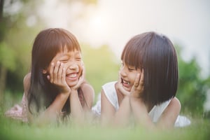 little-girl-with-friend-lying-comfortably-grass-smiling_Low
