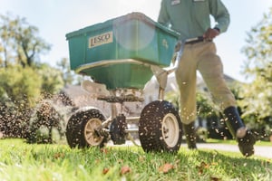 technician spreading fertilizer